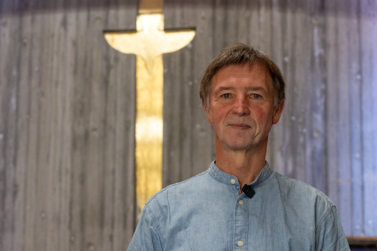 Paul Erik Wirgenes i kapellet på VID vitenskapelige høgskole. Et kors lyser opp bak ham. 